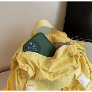 Détail du sac à dos en nylon jaune montrant la poche zippée et le rangement téléphone