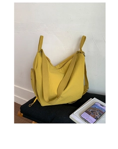 Detail of yellow nylon shoulder bag showing side zipper pocket and durable webbing strap