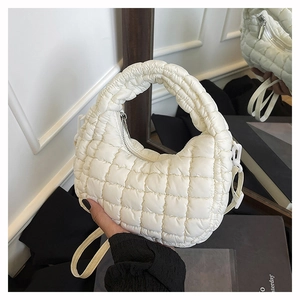 Detail of white quilted dumpling bag showing puffer nylon texture and crossbody strap