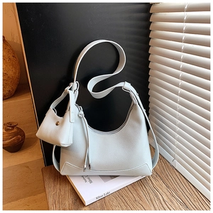 Detail of light blue pebble leather hobo bag with matching mini coin purse on books