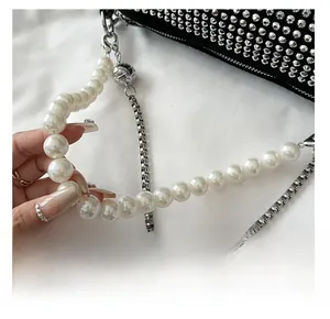 Detail of elegant faux pearl chain strap with silver metal links on a black handbag