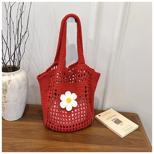 Détail du sac cabas au crochet rouge avec fleur de marguerite sur texture en maille tissée
