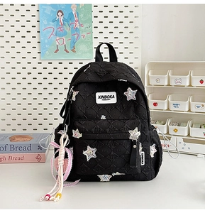 Detail of black quilted star backpack with sequined patches and woven rope pendant