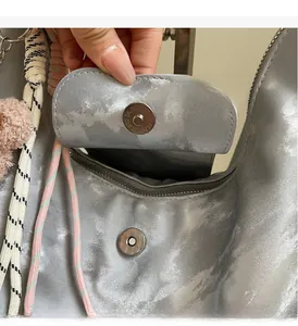 Detailed view of silver metallic textured tote with magnetic clasp and charm detail