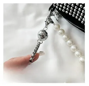 Detail of luxury white pearl and silver metal chain strap with textured bead on bag