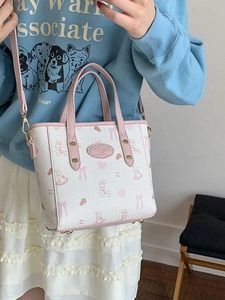 White and pink printed tote bag with rabbit pattern and adjustable strap on a female model