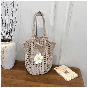 Gros plan détaillé d'un sac cabas en crochet beige avec une fleur de marguerite