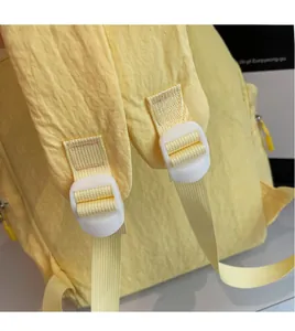 Détail de la boucle blanche et de la sangle en nylon jaune du sac à dos de randonnée