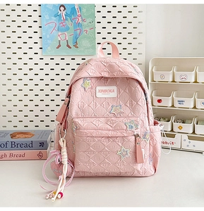 Pink quilted star backpack with heart charm displayed in a cozy school desk setting