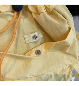 Détail du sac à dos en nylon jaune avec cordon orange et fermeture à bouton pression métal