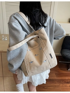 Grand sac cabas en toile beige avec broderies chiots et large bandoulière dans un salon