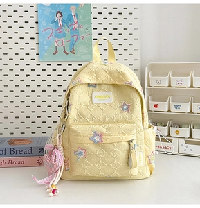Detail of yellow quilted backpack featuring colorful star patches and heart charm