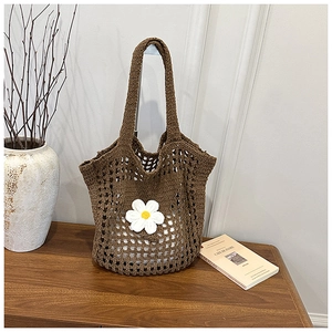 Détail d'un sac cabas en crochet marron avec marguerites blanches sur bois