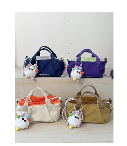 Detail view of colorful nylon shoulder bags with monster charms and drawstring interior