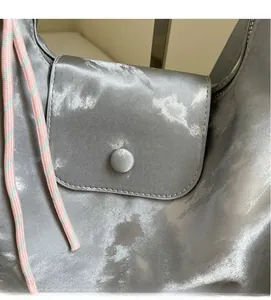 Detail view of silver satin texture and woven rope decor on this casual tote bag