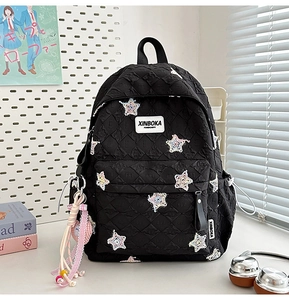 Detail of black quilted backpack with colorful star sequins and side pocket heart charm