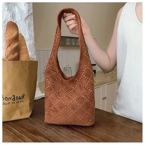 Dettaglio borsa tote in pelle scamosciata marrone con borchie argentate a rombi