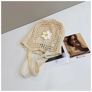 Détail de la texture du sac fourre-tout en crochet beige avec un ornement de marguerite