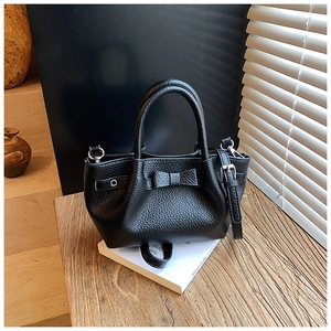 Dettaglio borsa a secchiello in pelle martellata nera con fiocco decorativo e finiture argentate