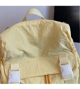 Détail d'un sac à dos en nylon jaune montrant le tissu souple et la boucle en plastique