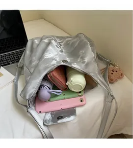 Silver metallic shoulder bag showing large capacity with umbrella, wallet, and tablet inside