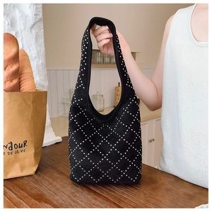 Dettaglio della borsa hobo in pelle scamosciata nera con borchie su un tavolo in legno