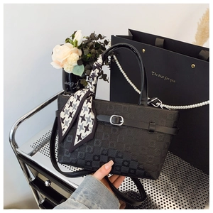 Détail du sac à main en cuir noir texturé avec boucle argentée et foulard en soie pied-de-poule