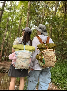 Outdoor backpacks with roll-top closure and bungee cord system in forest setting
