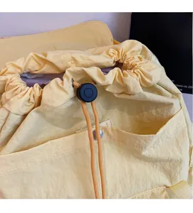 Détail du sac à dos en nylon jaune clair avec fermeture à cordon et poche à bouton-pression