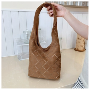 Dettaglio della borsa tote in camoscio marrone con borchie argentate a rombi e tracolla