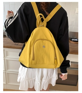 Macro detail of vibrant yellow textured nylon backpack with metallic circular logo