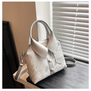 Detailed view of silver shirt-collar handbag with decorative buttons and leather texture