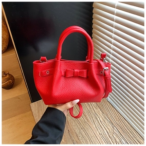 Dettaglio della borsa a secchiello in pelle rossa martellata con fiocco e metallo