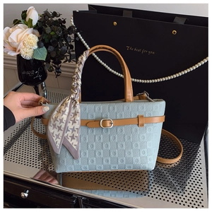 Détail du sac seau bleu clair avec poignées marron et décoration élégante en foulard