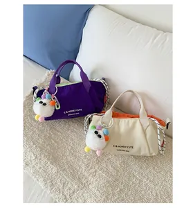 Detail view of canvas Boston bags in purple and cream with cute plush monster charms