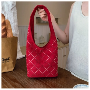Dettaglio borsa tote in pelle scamosciata rossa con borchie argentate e manico integrato