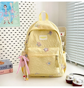 Detailed close-up of light yellow quilted star backpack with cute bow and heart charm