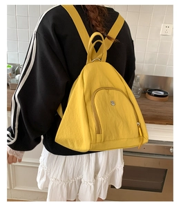 Detail of bright yellow nylon backpack showing front zip pocket and sturdy strap handle