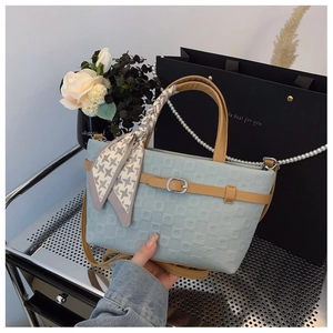 Détail du sac seau bleu clair avec sangle en cuir marron et poignée écharpe pied-de-poule