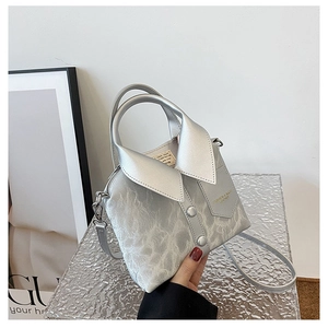 Macro view of shirt-shaped silver handbag with marble texture and collar details