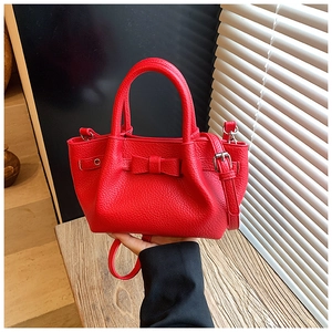 Dettaglio borsa a secchiello in pelle martellata rossa con fiocco e finiture argento