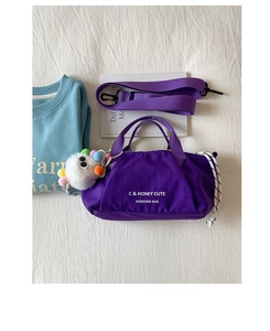 Purple canvas bag detail with white lettering, wide strap and soft pompom charm