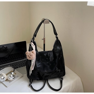 Detail of black multi-functional backpack with cute bear charm and striped scarf decoration
