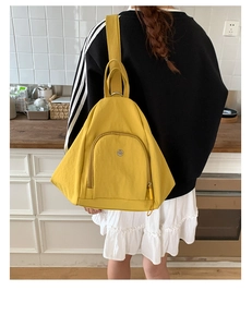 Close-up of bright yellow multifunctional backpack showing circular metal logo on front pocket