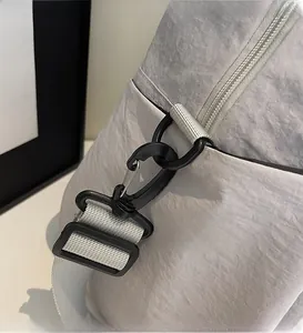 Détail du crochet noir réglable sur la bandoulière d'un sac cabas en toile grise
