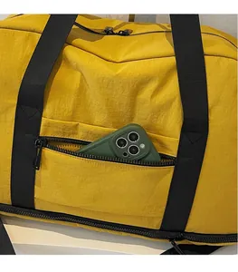 Detail of a large yellow fitness bag showing a front zipper pocket with a smartphone inside