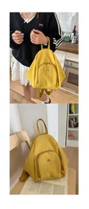 Detail view of yellow nylon backpack featuring large main compartment and front zip pocket