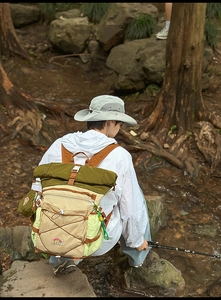 Detail of color-block roll-top outdoor backpack with bungee cord in forest setting