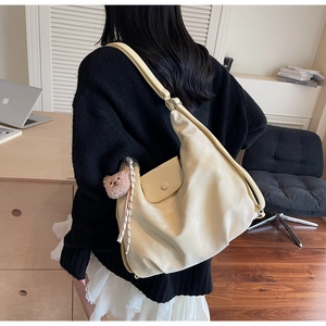 Detail of beige PU leather tote bag with a cute bear pendant and stripe ribbon