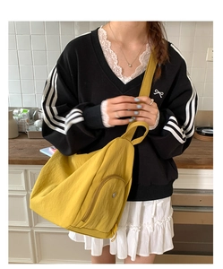 Detail of yellow nylon half-moon crossbody bag showing the side zipper and strap